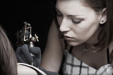 girl tattoo artist works on the client