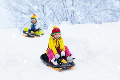 little girl enjoying a sleigh ride. child sledding. toddler kid riding a sledge. children play outdoors in snow. kids sled in the alps mountains in winter. outdoor fun for family christmas vacation.