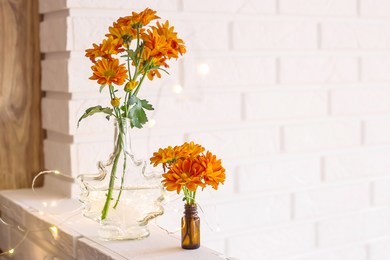 large and small bouquets of orange chrysanthemums in vases in the autumn bright home interior. comfort and beauty at home