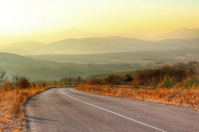 a road weaving in the distance aith mountain range during sunset