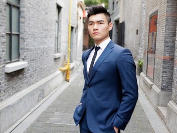 portrait of a handsome businessman in suit posing outdoor, close up upper body view. attractive male hipster chinese model.