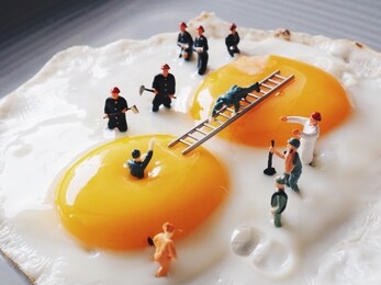 close up miniature people explorer fall in yolk then the team trying to helping.