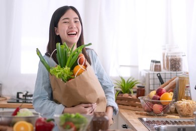 young asian woman in the kitchen and holding grocery shopping bag
