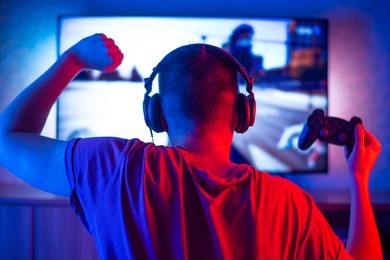 rear view of a young player playing video games on an fps console at home