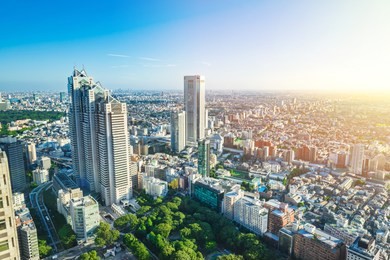 asia business concept for real estate and corporate construction - panoramic modern city skyline aerial view of shinjuku area under bright blue sky and sun in tokyo, japan