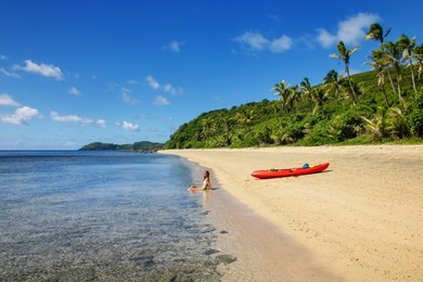 young woman with red sea kayak on a sandy beach, drawaqa island, yasawas, fiji
