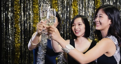 young women clinking champagne high celebrating before marriage on single party at nightclub. group of asian girls cheerfully toasting wine together celebrating. female models in glamour party dress.