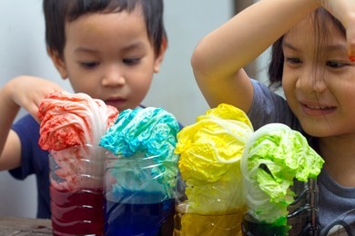2 sibling asian kids making simple science experiment at home.2 years and 6 years old kid make how plants absorb water and nutrients up through their stems by using  cabbage leaves and food coloring.