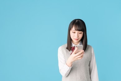 asian school girl holding a smart phone.
