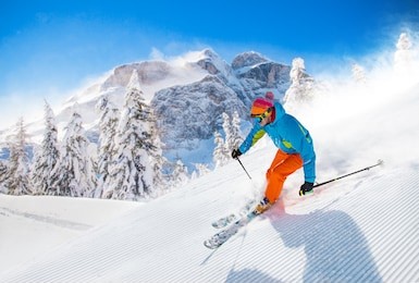 skier skiing downhill during sunny day in high mountains