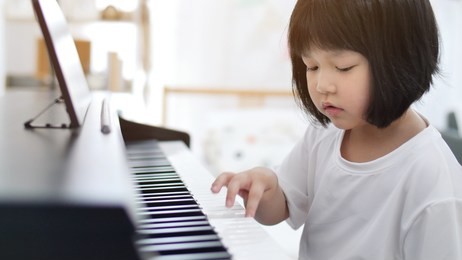happy little asian girl playing piano