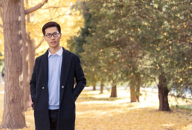 the handsome asian man is in the park in autumn.