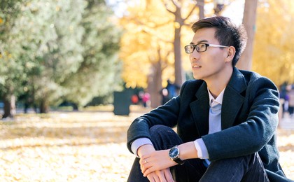 the handsome asian man smiles in the park in autumn.