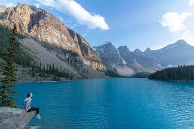 woman sitting looking at mountains at moraine lake in banff national park.