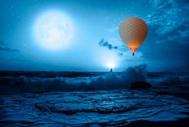hot air balloon over the stormy sea against super blue full moon and lighthouse at night" elements of this image furnished by nasa"
