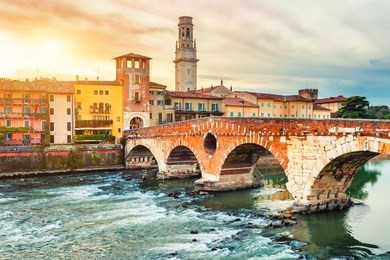 bridge ponte di pietra and ancient buildings at sunset in verona, italy. 