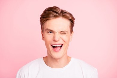 close-up portrait of nice cute lovely attractive positive cheerful cheery well-groomed guy in white t-shirt flirting opened mouth isolated over pink pastel background