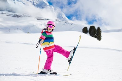 child skiing in the mountains. kid in ski school. winter sport for kids. family christmas vacation in the alps. children learn downhill skiing. alpine ski lesson for boy and girl. outdoor snow fun.