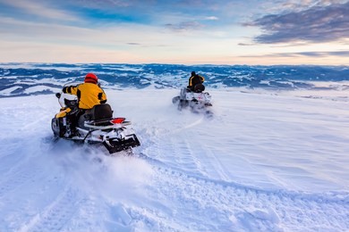 two men are riding snowmobile in mountains. beautiful morning light. blue shadows.