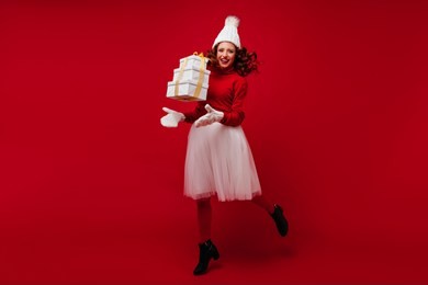 full-length portrait of appealing ginger woman dancing at christmas party with gift. indoor shot of adorable girl in white skirt having fun in new year.