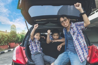 happy family on a road trip, sitting in trunk of car