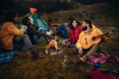 group of young people around camp fire.