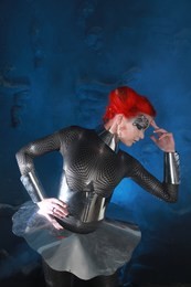 pretty redhaired futuristic girl with faceart make-up wearing spandex catsuit and steel corset