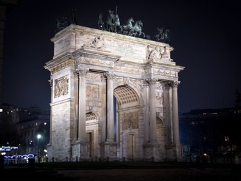 the arco della pace stands at the center of a pedestrianized plaza, at the edge of the sempione park