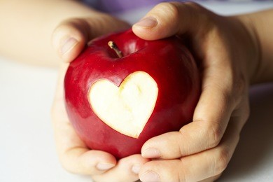 woman's hand with apple, which cut a heart