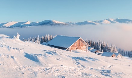 fantastic winter landscape with wooden house in snowy mountains. christmas holiday concept