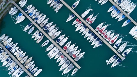 aerial view of a lot of white boats and yachts moored in marina on a turquoise water, during a summer season