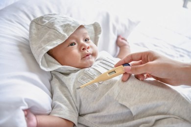newborn concept. the baby is sick in the bedroom. parents check their illness with thermometers.