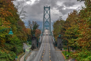 lions gate bridge as seen from stanley park in  vancouver, canada with autumn leaves. the lions gate bridge, opened in 1938, officially known as the first narrows bridge, is a suspension bridge.