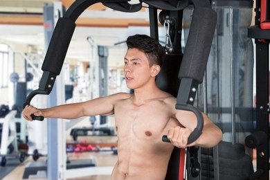 picture of a muscular man exercising with fitness machine at the gym center