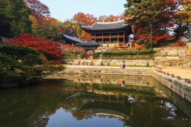 a wide view of changdeokgung in autumn with a couple wearing hanbok