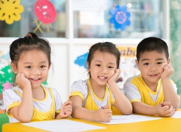 asian children sitting behind the desk in the room
