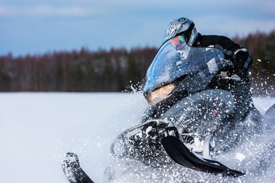 in deep snowdrift snowmobile rider driving fast. riding with fun in white snow powder during backcountry tour. extreme sport adventure, outdoor activity during winter holiday on ski mountain resort.