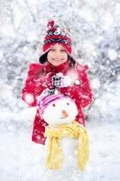 girl makes a snowman outside in winter time