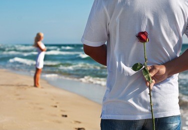 loving couple, man with rose waiting his woman on the sea beach at summer, the romantic, wedding or valentines day concept