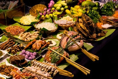closeup view of exotic night market street food in southern china. dai ethnic cuisine. table with various fish and vegetables on skewers in jinghong, xishuangbanna, yunnan province, china.