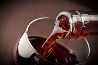 pouring red wine on background