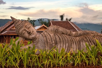 traditional reclining buddha near chinese theravada dai temple with view of evening sky. classical buddhist iconography in jinghong, china (xishuangbanna, yunnan province, china).