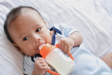 newborn concept. mom is breastfeeding in the bedroom. 
little baby is drinking milk in the bedroom. mother is raising and caring baby.