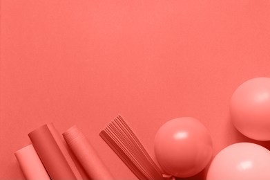living coral color background with wrapping paper rolls for gifts and balloons, copy space
