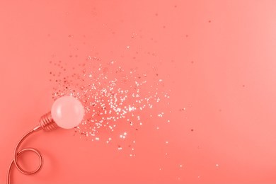 trend photography on the theme of the color of the year panton 2019 - living coral. one decorative lamp on a light background with a scatter of sequins symbolizing the rays of light from the lamp.