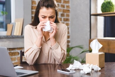 young businesswoman suffering from allergy at workplace 