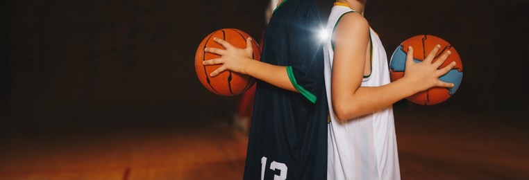 two boys basketball team players holding basketballs on the wooden court. basketball training for kids. horizontal background of youth basketball players, copy space