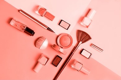 creative flat lay of fashion bright nail polishes and decorative cosmetic on a colored in color of year 2019 living coral background. macro color 16-1546 background. beauty blogger concept. top view