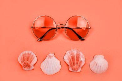 summer flatlay with round gradient sunglasses and sea shells on the bright living coral backfround.