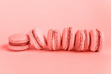 sweet almond macaron or macaroon dessert cake colored in trendy color of year 2019 living coral background. bright macro color 16-1546. minimal food bakery concept. flat lay top view copy space